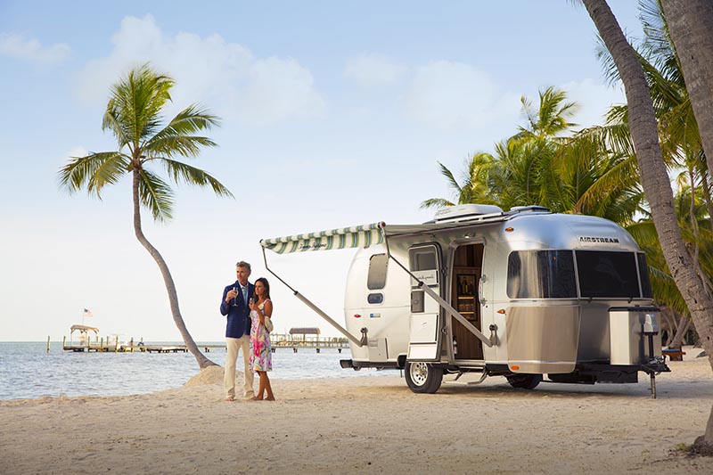 Couple on beach with Airstream Tommy Bahama Travel Trailer