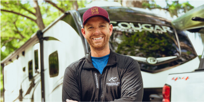 Man smiling in front of an RV