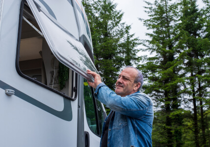 Man opening the window of an RV.