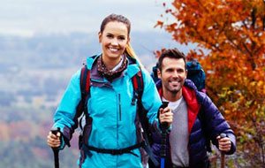Couple hiking up a hill covered in fall foliage