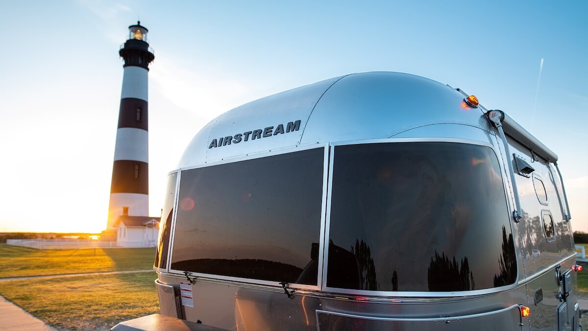 Close up of an Airstream trailer with a lighthouse in the background