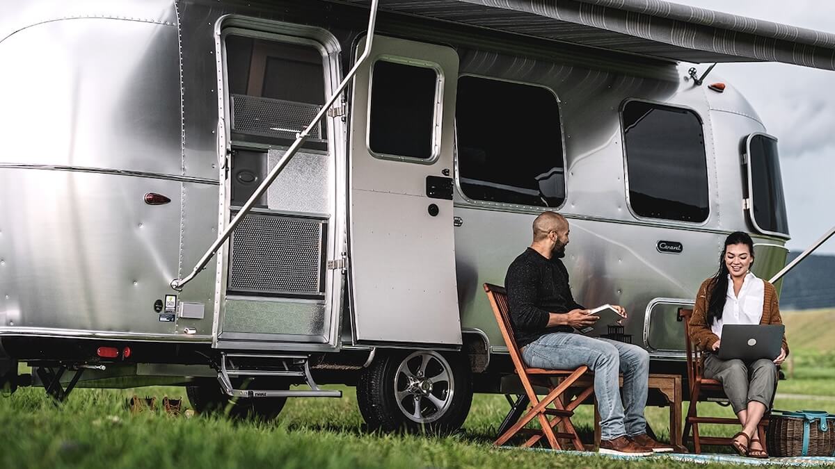 A couple sitting outside their Airstream trailer