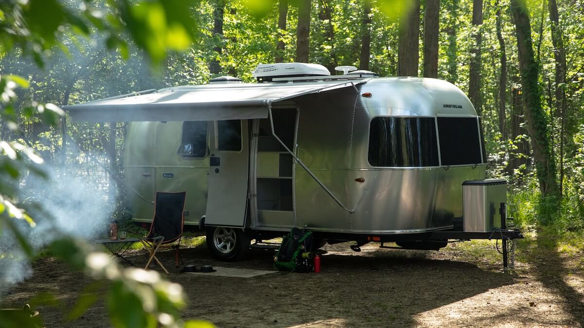 A young couple sitting in the back of their Airstream trailer