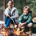 Mother and son roasting marshmallows on a campfire.