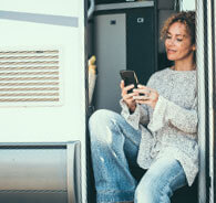 Woman sitting in a camper and looking at her phone.