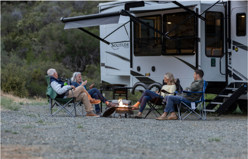 family around a campfire outside their RV