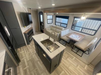 Very spacious living area with opposing slides, kitchen center island, TV and fireplace of new 2025 Prime Time LaCrosse 3510DB