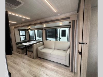 Living area slide contains booth dinette with storage and trifold sofa or theater seating in new 2026 East to West Alta 3150KBH