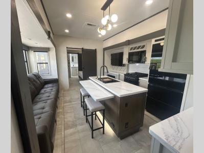 Spacious living area with 5 piece sectional recliner sofa and kitchen area of 2026 Prime Time Sanibel 39BUNK RV