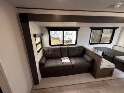 Generous living area slide has a sofa and dinette in the new 2026 Prime Time Avenger 26DBS RV