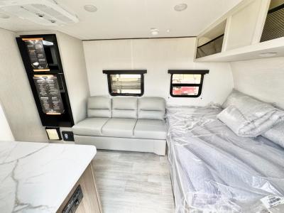 Queen bed next to sofa in roomy new 2026 prime Time Avenger LT 17RK RV