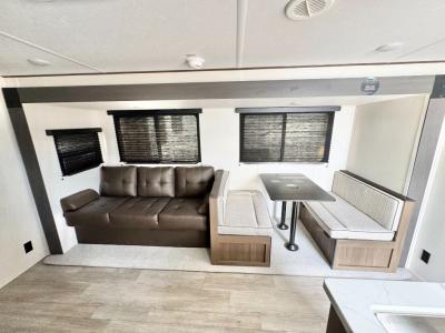 Living area slide with sofa and dinette in new 2026 Prime Time Avenger 25RBS RV