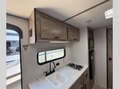 Tidy kitchen with 2-burner stove, microwave, and refrigerator in new 2026 Gulf Stream Conquest Super Lite 178RB RV