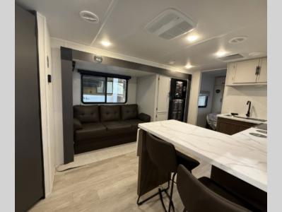 Sofa sleeper in living area slide opposite modern kitchen in new 2026 Prime Time Avenger 25MKO RV