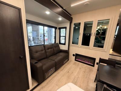 Large sofa in slide containing pantry and fridge in living area of new 2026 Forest River Vengeance Rogue Armored 4015 RV