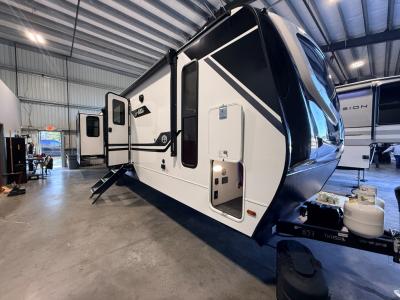 Front/side view of new 2026 East to West Alta 3175RK travel trailer with 18' power awning and fold down patio