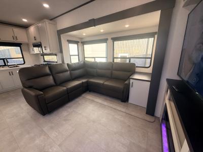 Sectional sleeper sofa in living area slide opposite 65"smart TV and fireplace in new 2026 Prime Time Crusader KING 33 RV