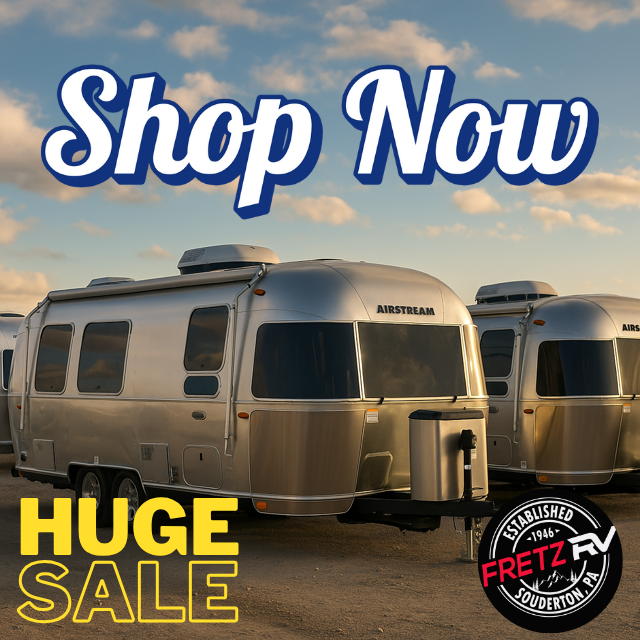 Three used Airstream travel trailers parked on a gravel lot under a partly cloudy sky, showcasing their polished aluminum exteriors