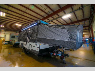 Angled Front Exterior View: A dynamic front view of the pop-up RV with an extended canopy.