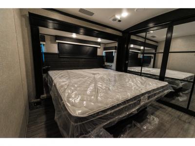 Bedroom interior of the Jayco Pinnacle 36KPTS featuring a king-size bed, overhead storage, and dual side windows.