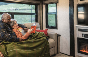 couple in their RV reading in front of the fireplace