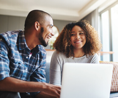 couple smiling in front of a laptop