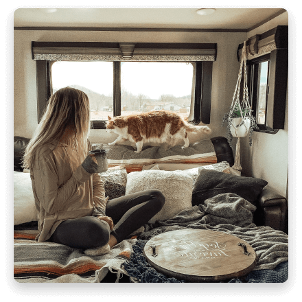woman looking out the window of her RV holding a cup of coffee