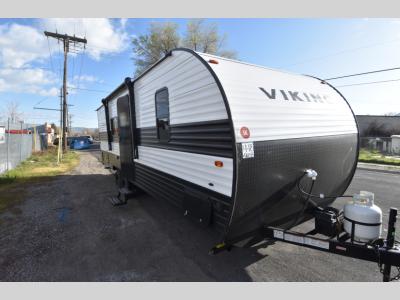 Front angle of 2024 Viking 26BH travel trailer showing entry door and propane tanks