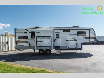 Driver’s side exterior of the 2024 Durango D321RKT with three slide-outs extended and rear kitchen layout visible.
