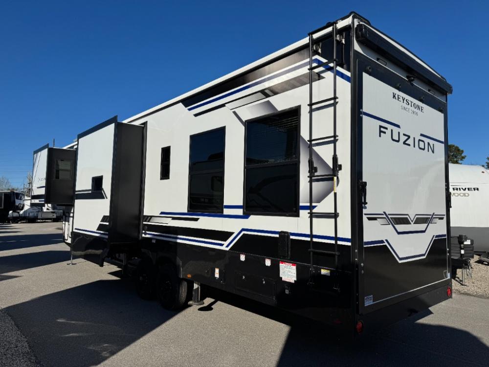 Exterior side view of 2026 Keystone Fuzion 373 toy hauler fifth wheel with dual awnings extended at Recreation USA