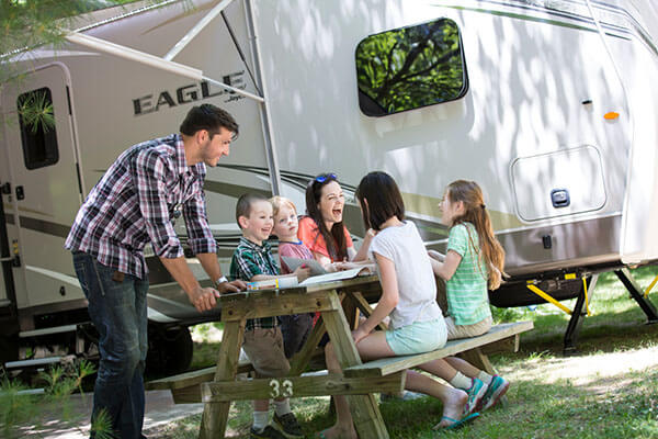 Family sitting at a picnic table outside their RV.