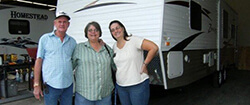 happy customers standing in front of a travel trailer