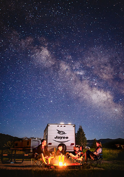 Family enjoying RV living at night with a campfire